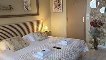 A double bed with a white quilt, two pillows, and a remote control on the bed.
