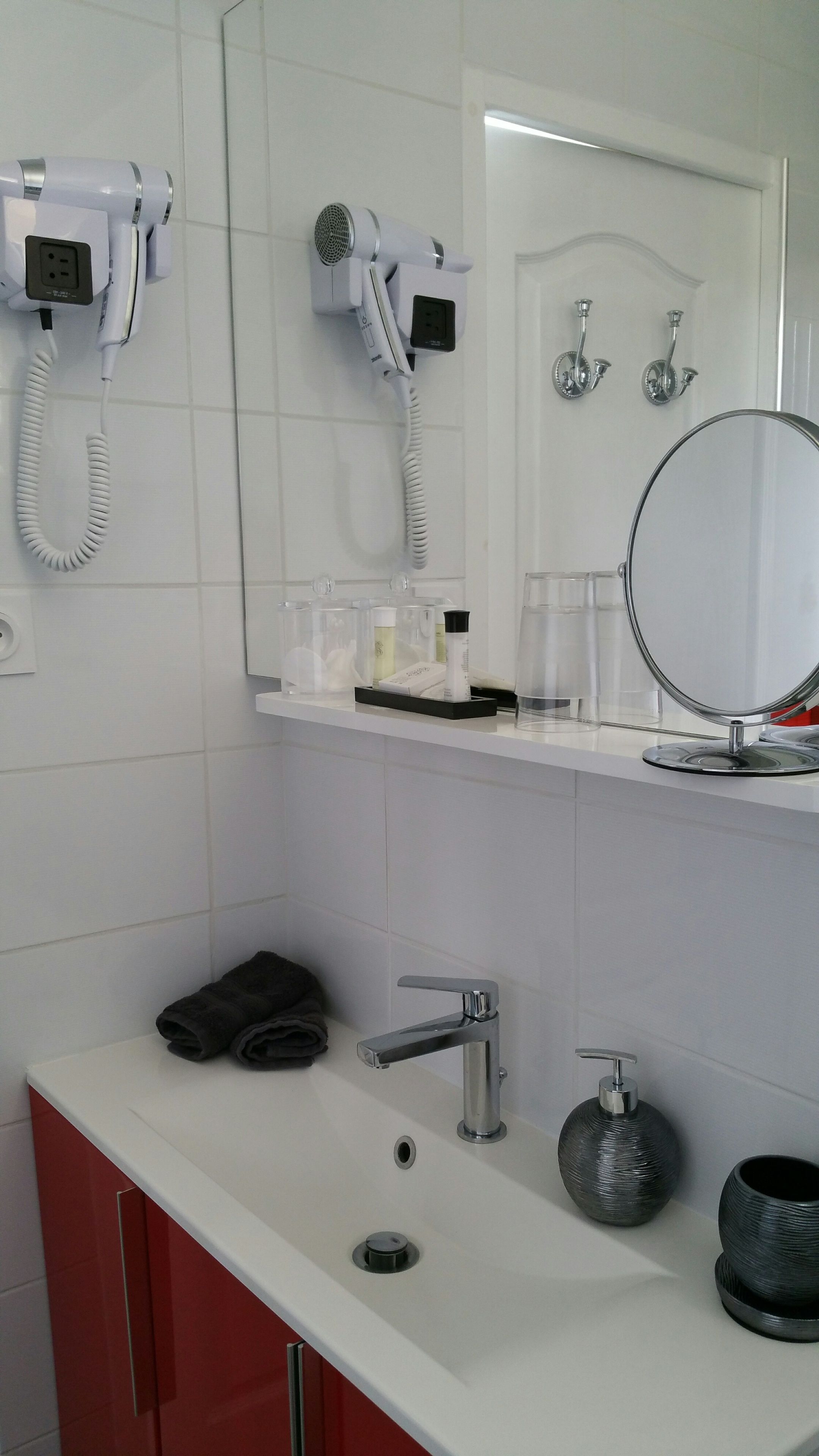 A bathroom with a white sink, a mirror, a hairdryer, and a shower.