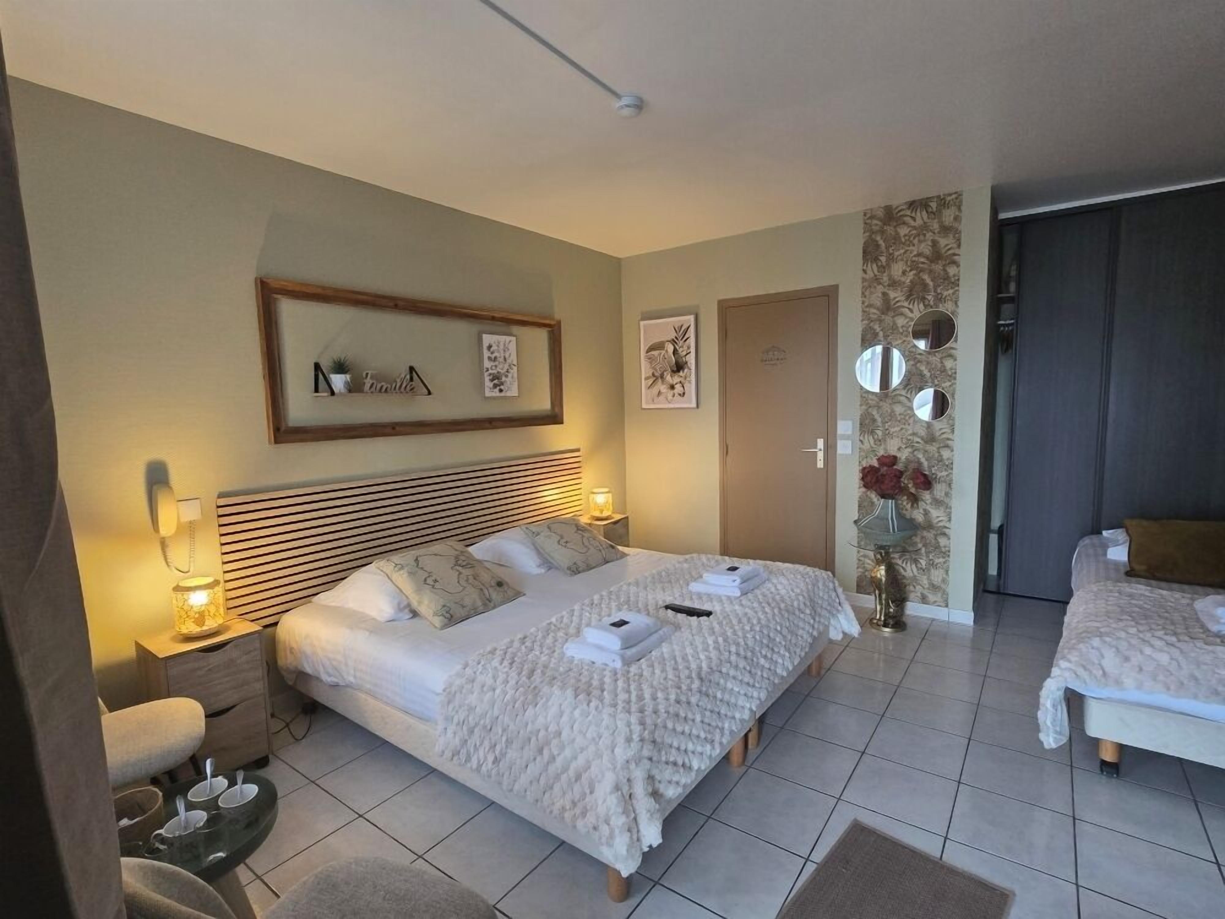 Una habitación de hotel con una cama grande, mesitas de noche, un pequeño rincón de descanso y una puerta que da a otra habitación.