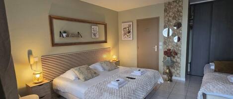Habitació d'hotel amb un llit gran, taules de nit, una zona de seients petita i una porta que dona a una altra habitació.