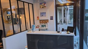Ein Empfangsschalter mit modernem Design, ein Kleiderständer, eine gerahmte Karte und ein dekorativer Spiegel.