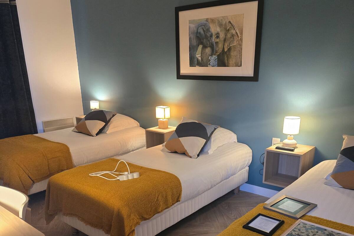 Ein Hotelzimmer mit zwei Betten, einem Schreibtisch und einem gerahmten Bild an der Wand.
