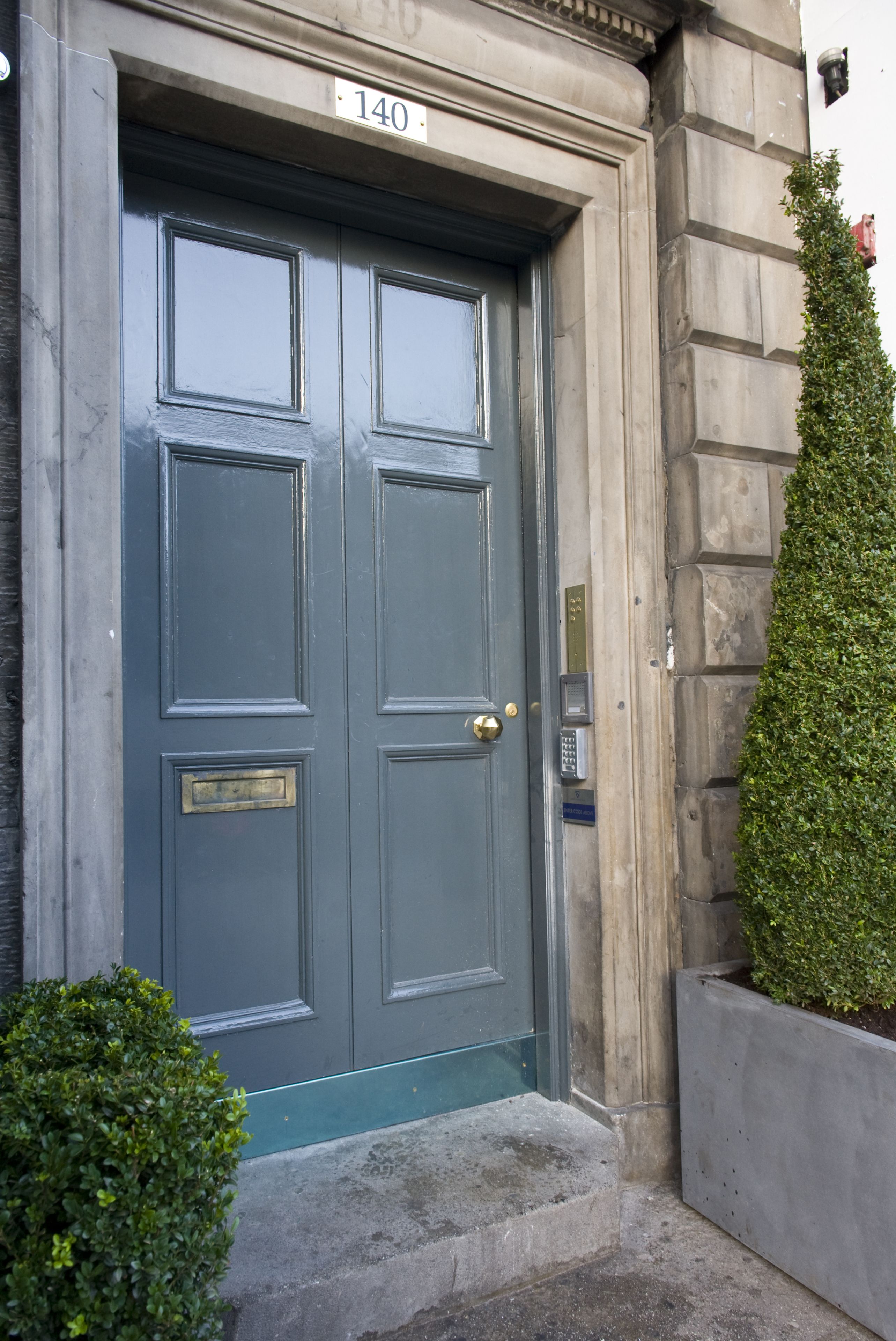 A double door with a number plate, a keypad lock, and a small step leading to the entrance.