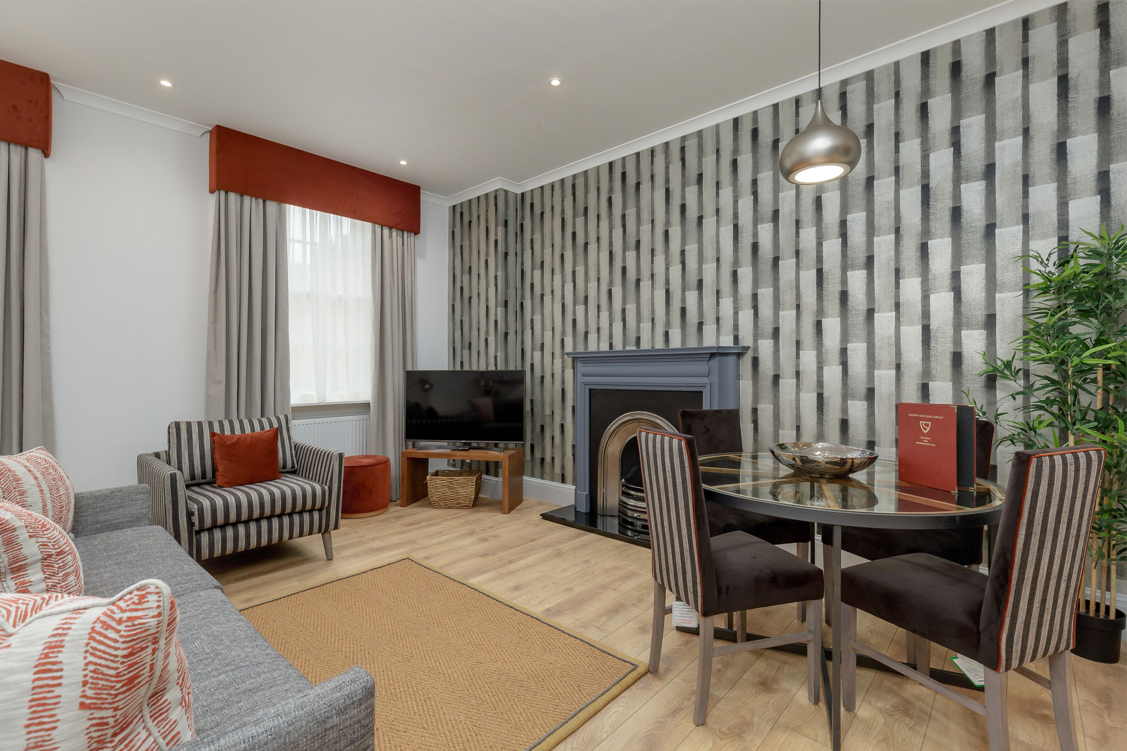 A living room with a sofa, armchairs, a TV, a fireplace, and a dining table with chairs.