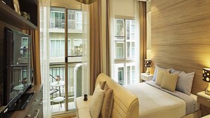 A hotel room with a large bed, a sofa, a TV, and a balcony with a view of the city. - The Gallery Jomtien Beach Pattaya Condo By Dome (Pattaya)