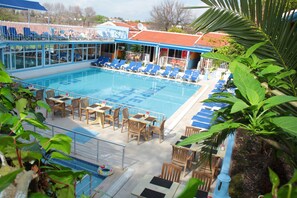 A swimming pool with lounge chairs and tables, surrounded by greenery. - Side Temple Hotel (Manavgat)