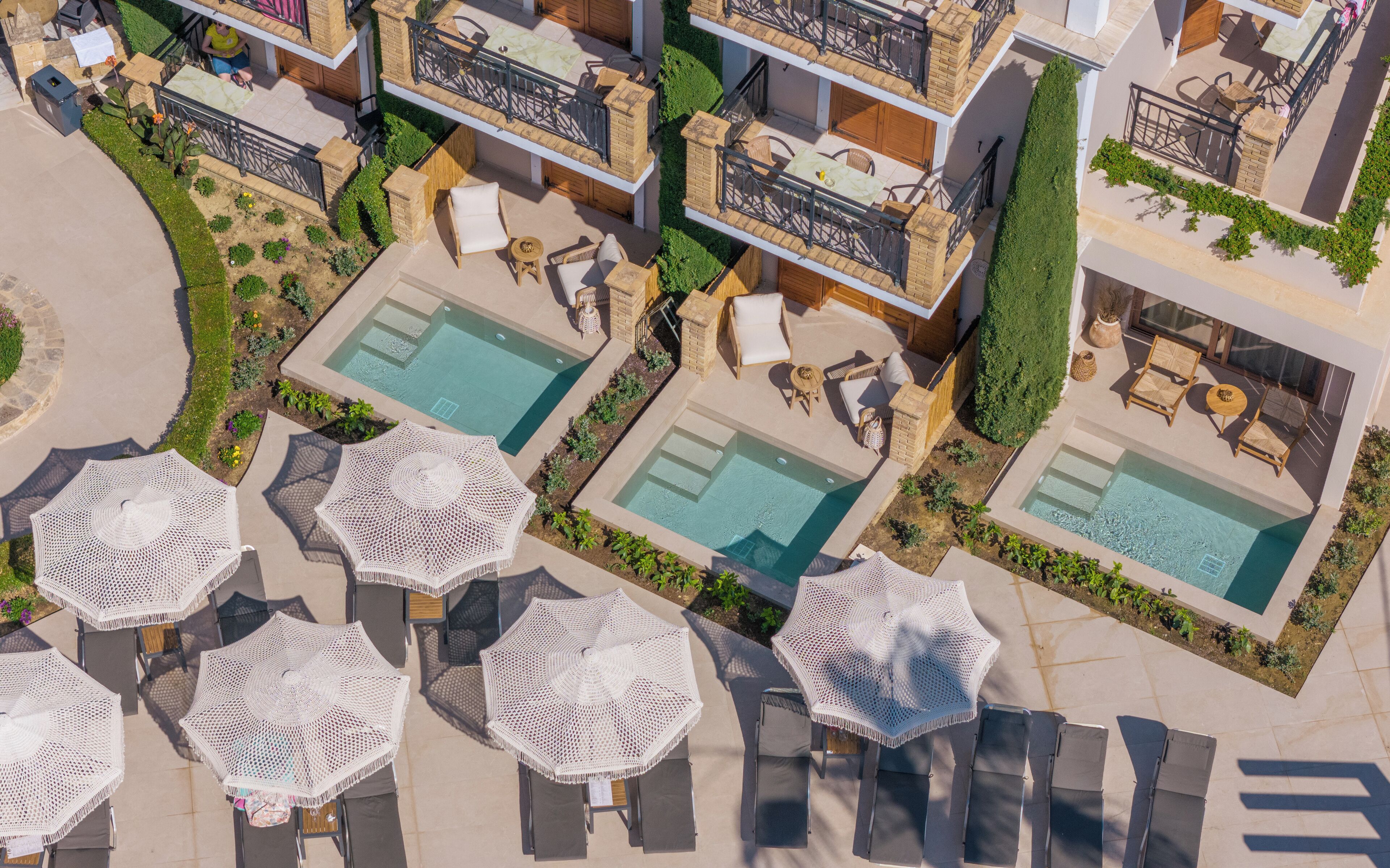 Vue aérienne d’un hôtel doté de plusieurs piscines, d’espaces de détente en plein air et d’un jardin bien entretenu.