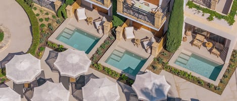 Vue aérienne d’un hôtel doté de plusieurs piscines, d’espaces de détente en plein air et d’un jardin bien entretenu.