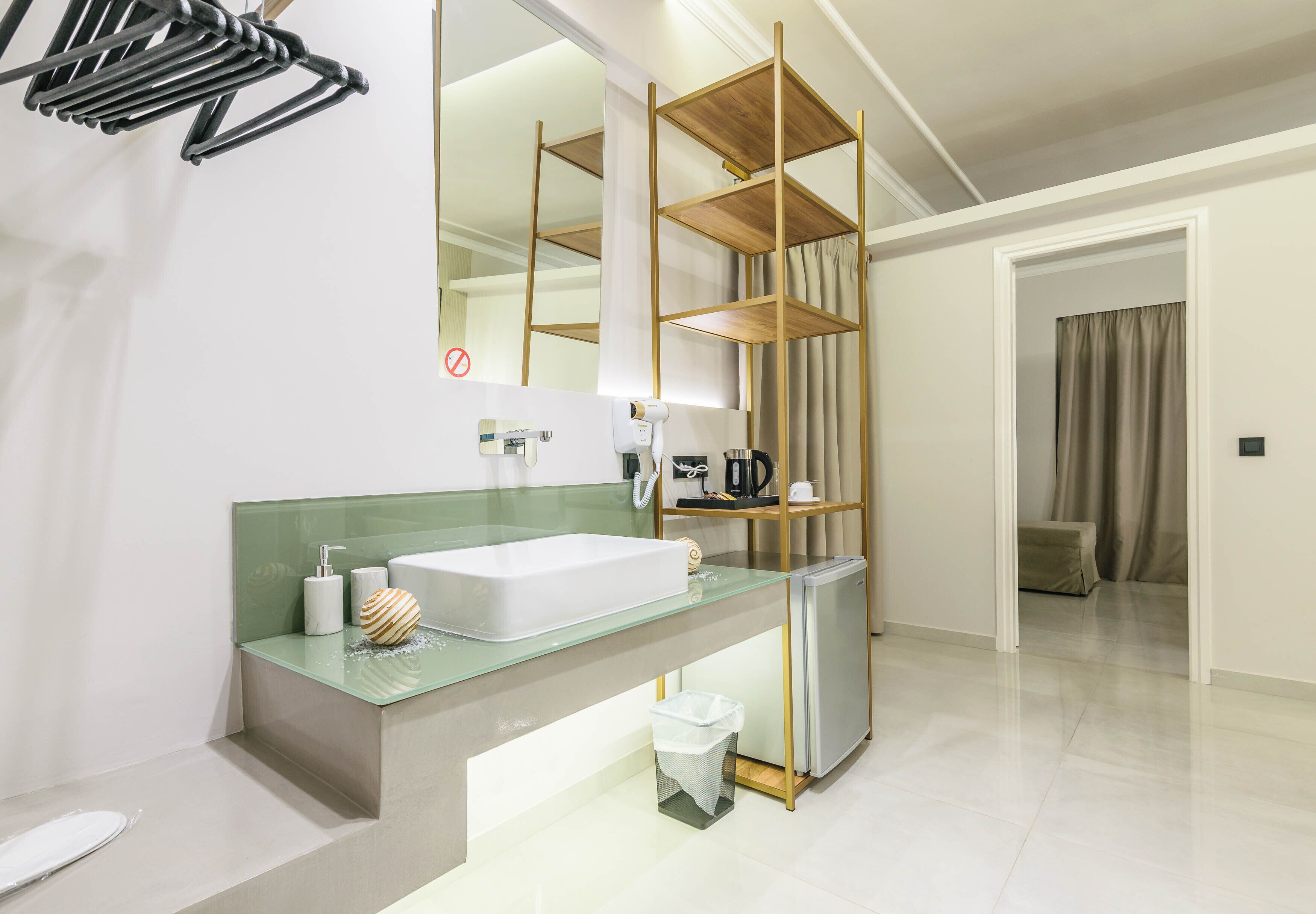 A modern bathroom with a glass sink, a mirror, a towel rack, and a wooden shelf unit.