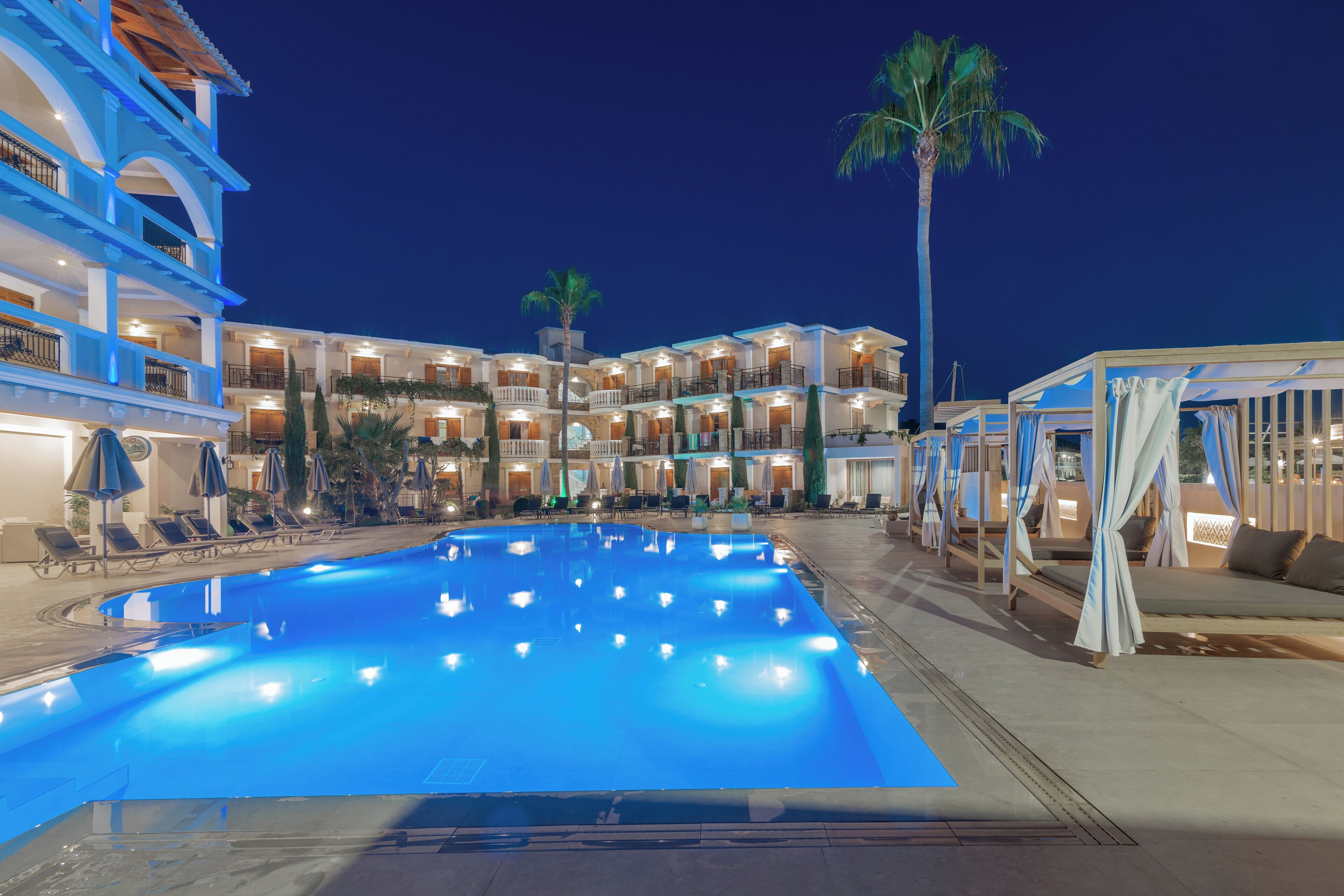 A hotel with a large swimming pool, multiple balconies, and outdoor seating areas.
