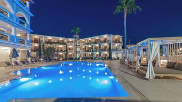 A hotel with a large swimming pool, multiple balconies, and outdoor seating areas.