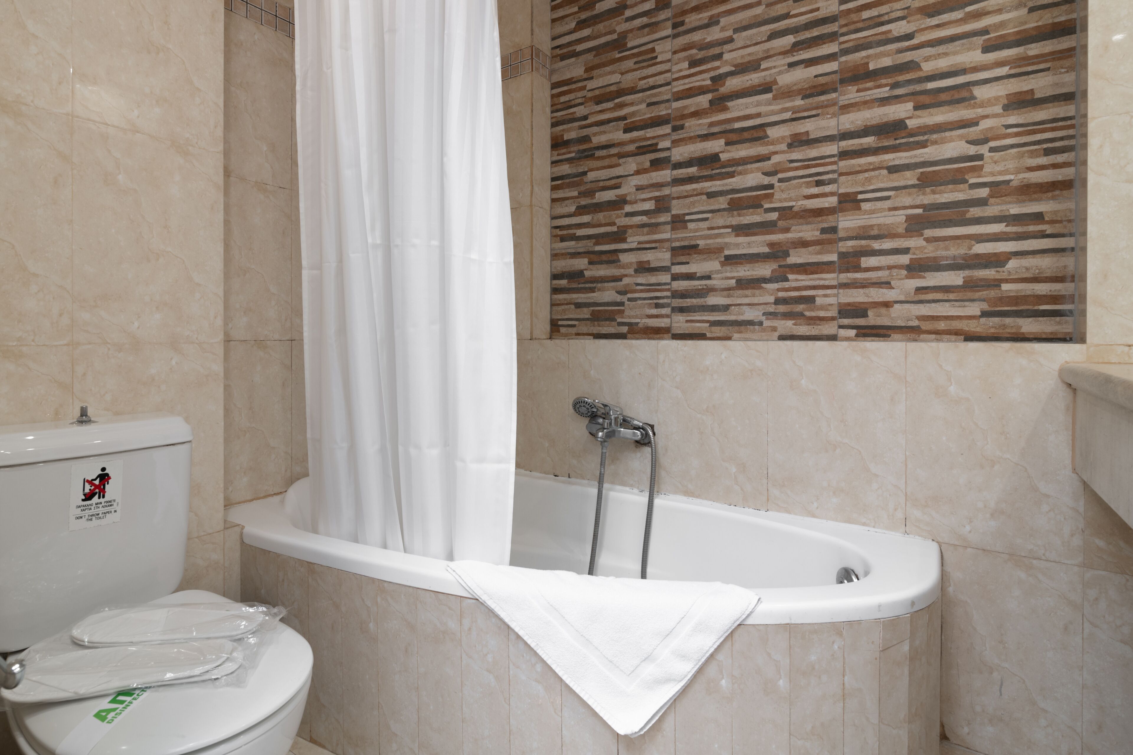 A bathroom with a bathtub, toilet, and a shower curtain.