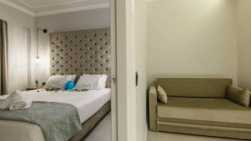 A hotel room with a bed, a headboard, a sofa, and a nightstand.