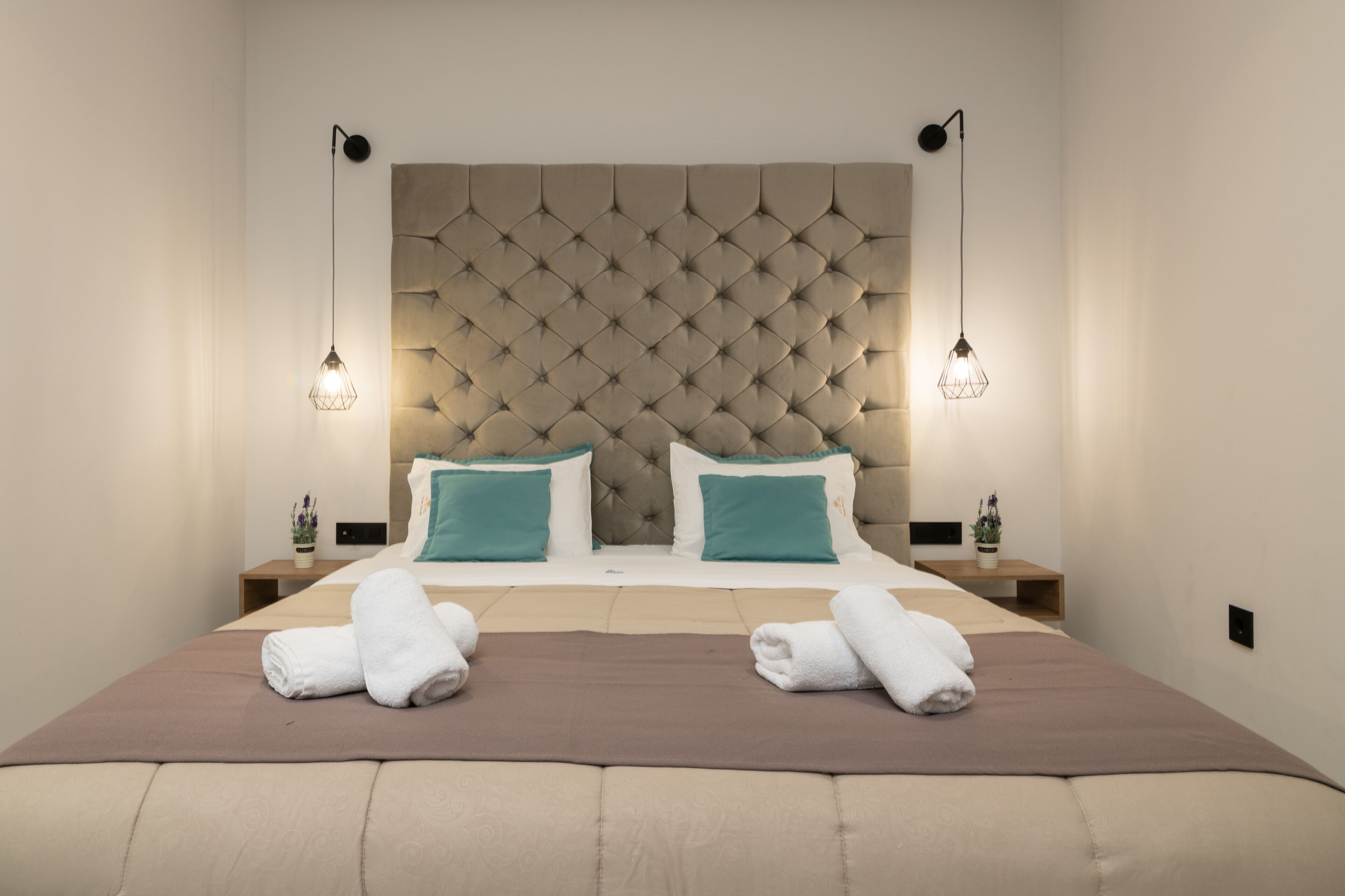 Une chambre d’hôtel avec un grand lit, deux tables de chevet et une tête de lit capitonnée.