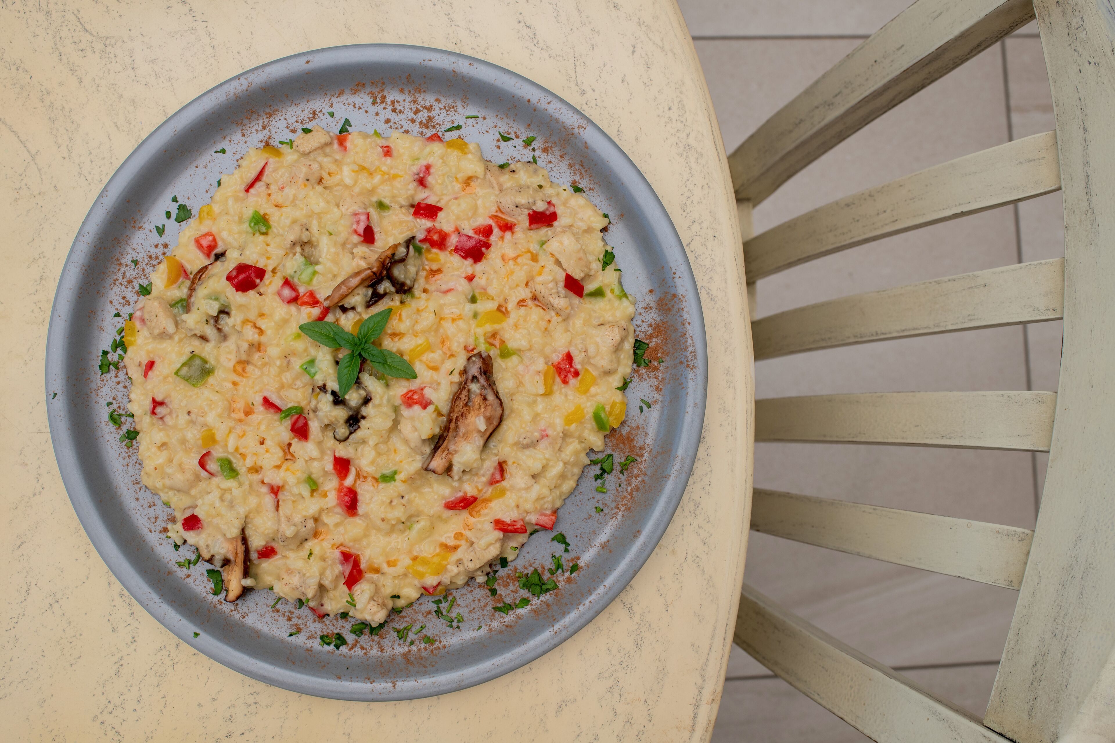 A plate of risotto with vegetables and herbs on a table.