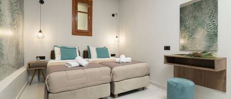 A modern bedroom with a double bed, bedside tables, a nightstand, a blue ottoman, a wooden shelf, and a large artwork on the wall.