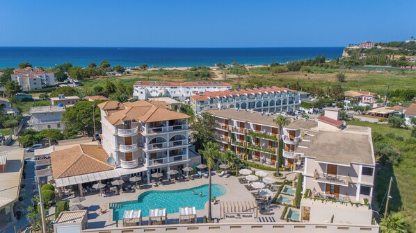 Un resort con varias edificaciones, una piscina y vista al mar.