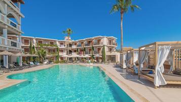 A resort pool area with multiple levels of balconies, sun loungers, and umbrellas.