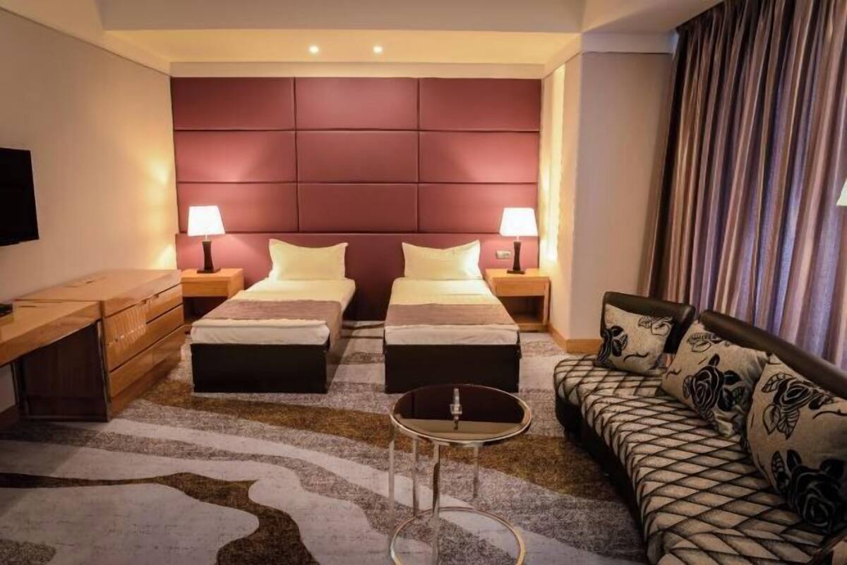Et hotelværelse med to senge, en sofa, et fjernsyn og et lille bord.