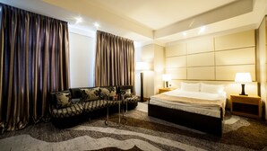 A hotel room with a bed, a sofa, two lamps, and curtains. - Absolute Hotel (Astana)