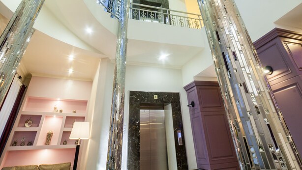 A multi-level interior with a central spiral staircase, a second-floor balcony, and a modern elevator. - Absolute Hotel (Astana)