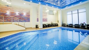 An indoor swimming pool with a blue tiled floor, a staircase, and a ceiling with a cloud design. - Absolute Hotel (Astana)