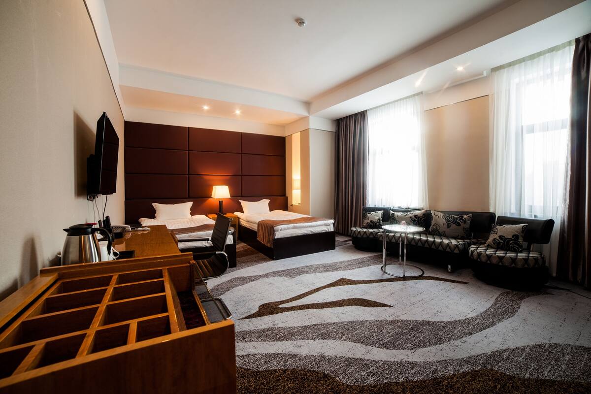 Et hotelværelse med seng, sofa, skrivebord og fjernsyn.