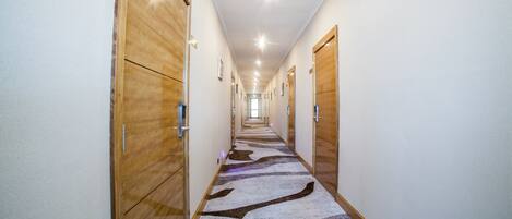 A long, narrow hallway with wooden doors on both sides and a patterned carpet.