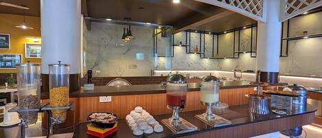 A buffet area with various food options, including cereal, fruits, and beverages.