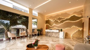 A modern hotel lobby with a reception desk, seating area, and a large window overlooking the city. - TGI STAR Holidays Yercaud (Yercaud)