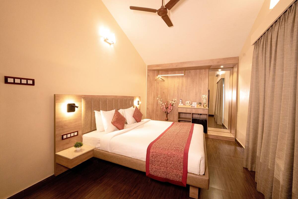 A modern hotel room with a large bed, a nightstand, a mirror, and a ceiling fan.