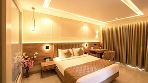 A modern hotel room with a large bed, bedside tables, a desk, and a chair. - TGI STAR Holidays Yercaud (Yercaud)