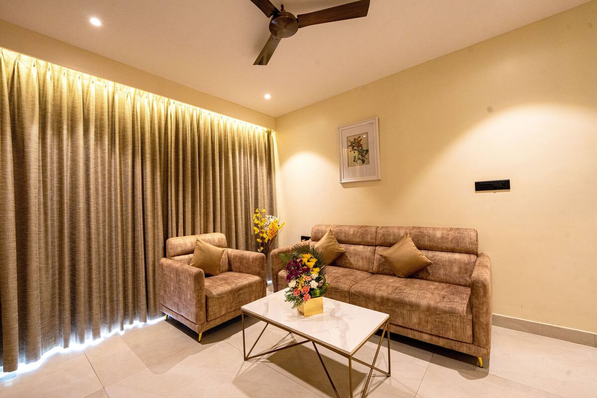 A living room with a sofa, two armchairs, a coffee table, and a ceiling fan.