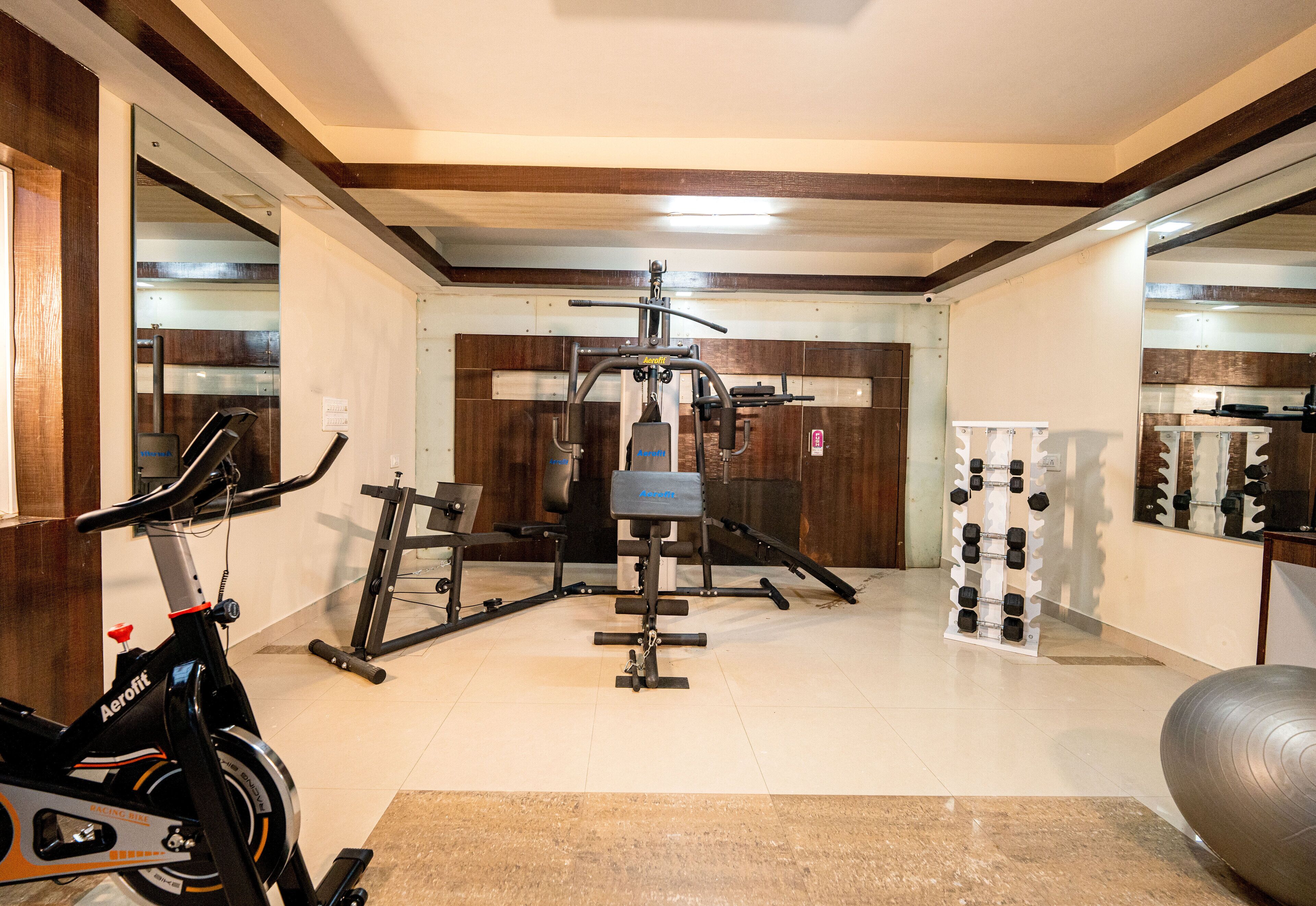 Un gimnasio en casa con equipo de ejercicio, una bicicleta estática y un muro con espejos.