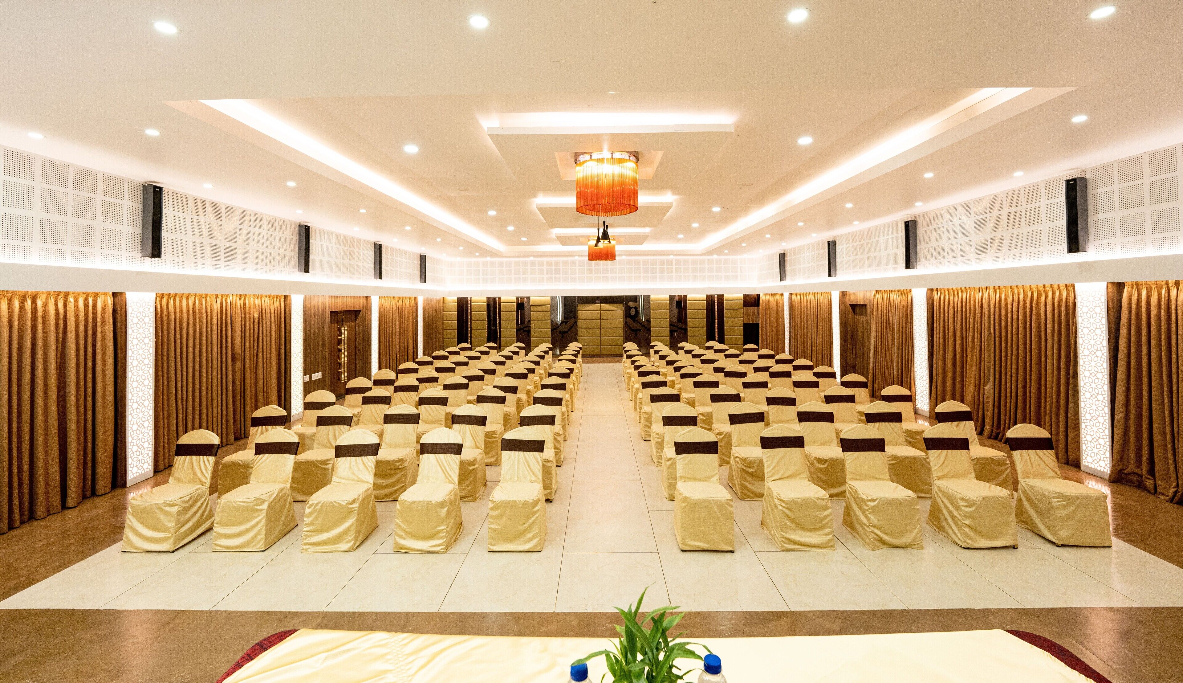 A conference room with rows of chairs, a stage, and a chandelier.