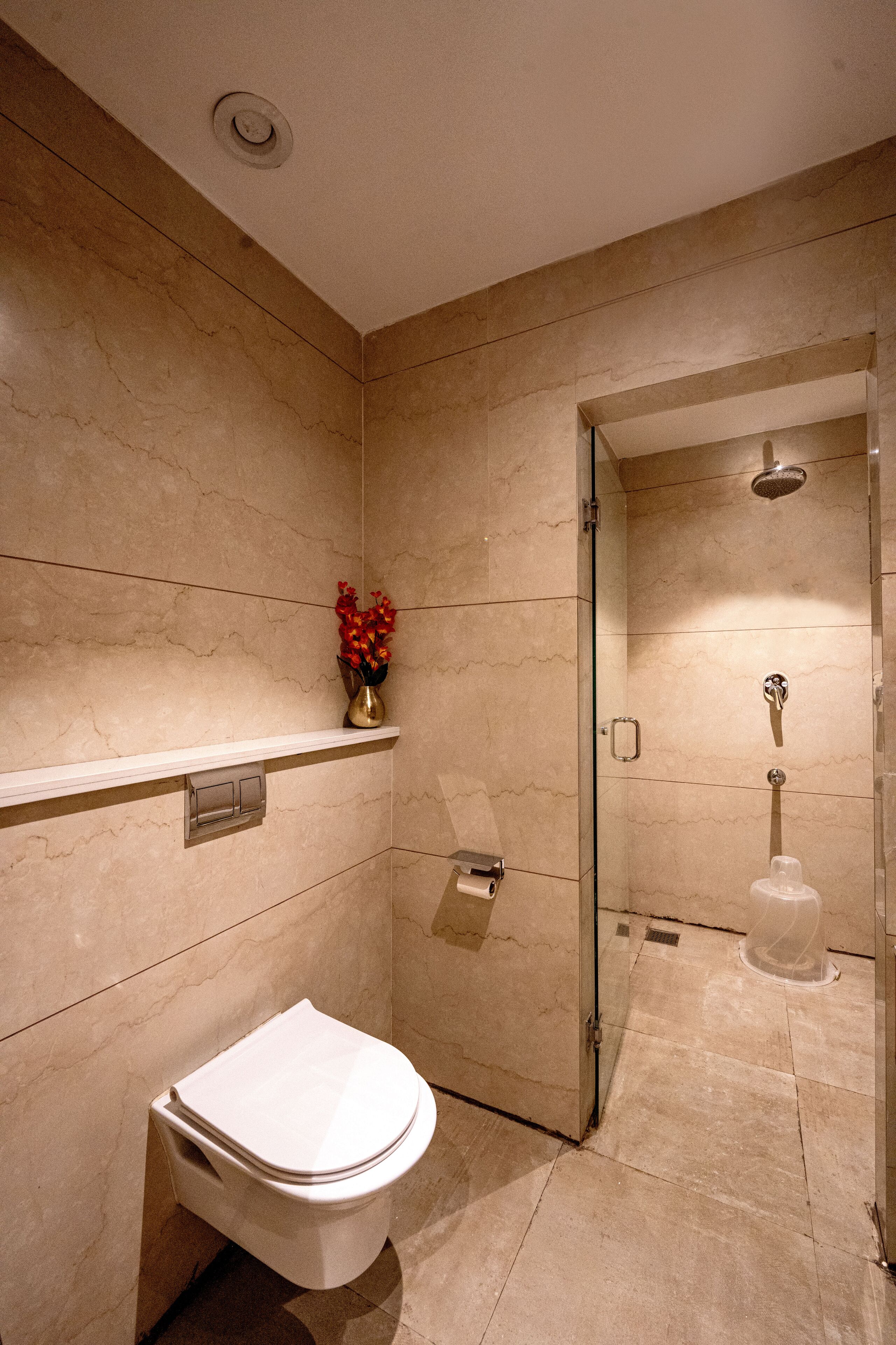 A modern bathroom with a toilet, a shower, and a marble wall.