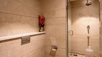 A modern bathroom with a toilet, a shower, and a marble wall.