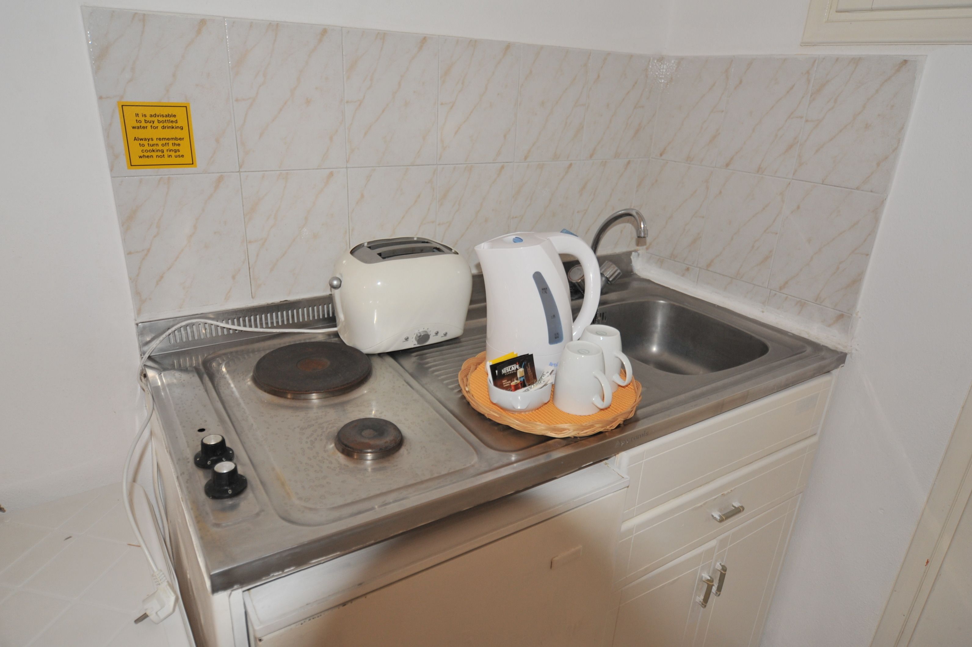 A kitchenette with a toaster, kettle, and a sink.