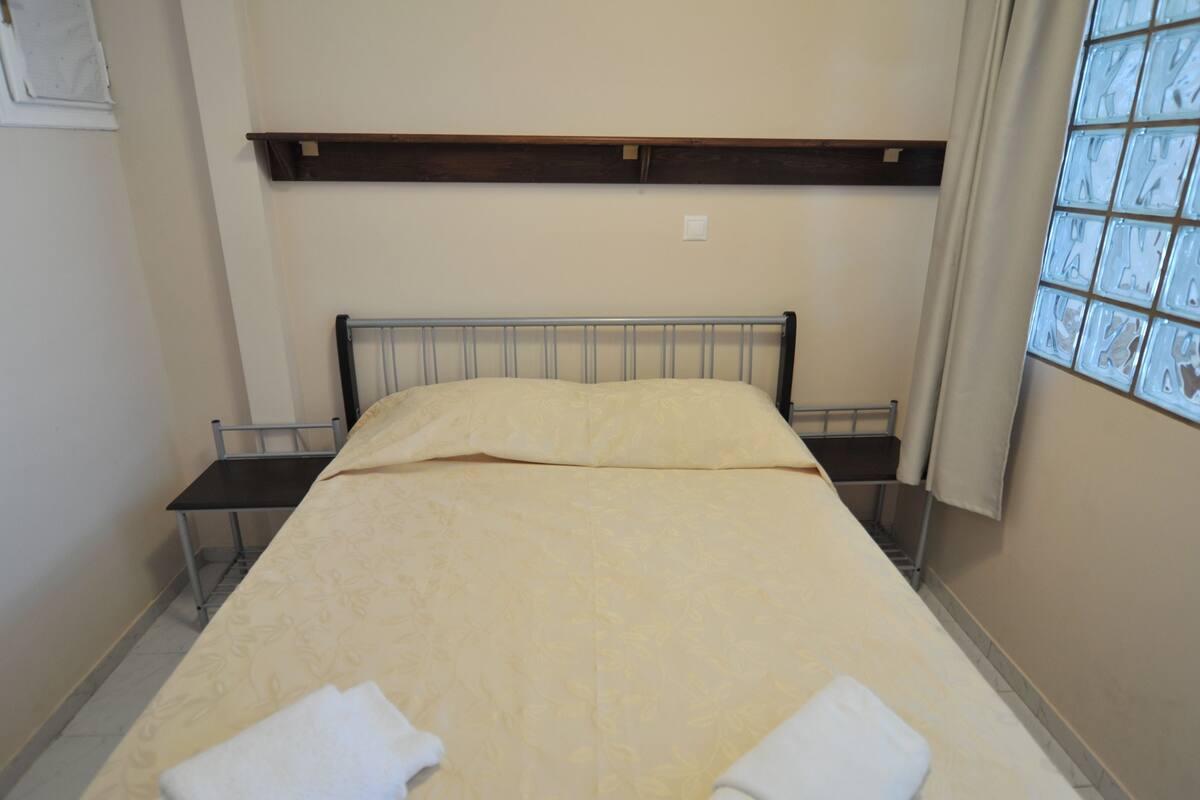 A single bed with a headboard, a bedside table, and a window with a view.