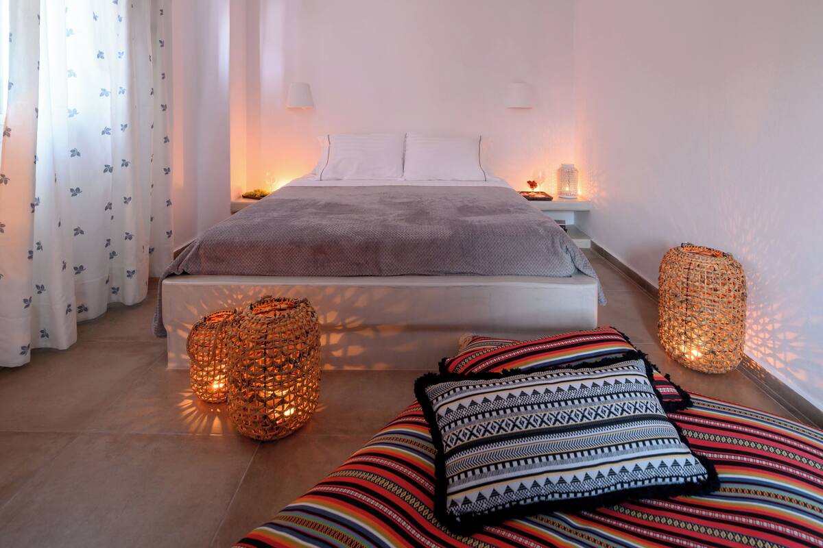 A minimalist bedroom with a bed, bedside lamps, and decorative woven baskets.