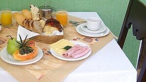 Una mesa de desayuno con platos de comida, una cesta de pan y dos vasos de jugo.