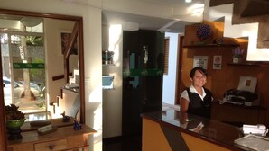 Un área de recepción con un escritorio de madera, un espejo y un tablón de anuncios.