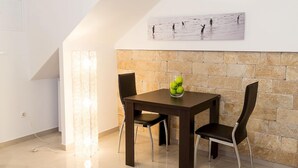 Un comedor con una mesa de madera oscura, dos sillas negras y una obra de arte colgada en la pared sobre la mesa.