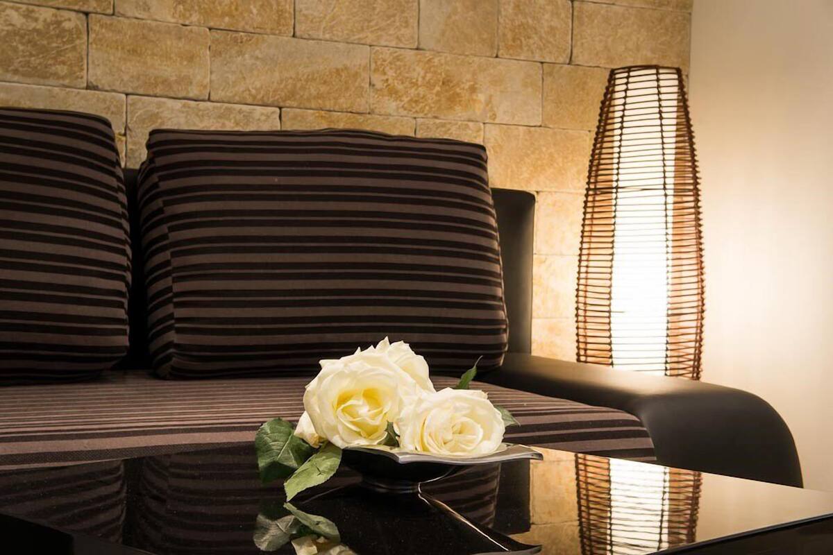 A modern room with a sofa, a tall floor lamp, and a small table with a vase of white roses.