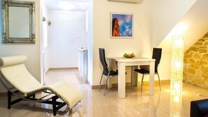 Una habitación con una silla reclinable, una mesa de comedor con sillas, un cuadro y una pared de piedra.