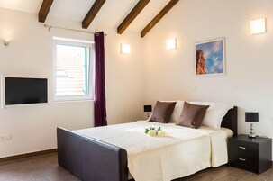 Ein Schlafzimmer mit einem Bett, Nachttischen, einem Fernseher und einem Fenster mit Vorhängen.
