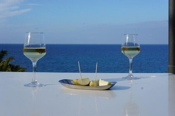 Two wine glasses on a table with a plate of food and a view of the sea. - Aphrodite Beach Hotel (Neo Chorio)