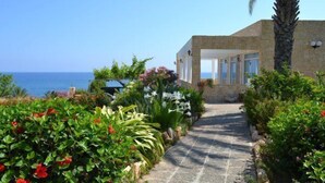 A pathway leading to a building with a view of the sea. - Aphrodite Beach Hotel (Neo Chorio)