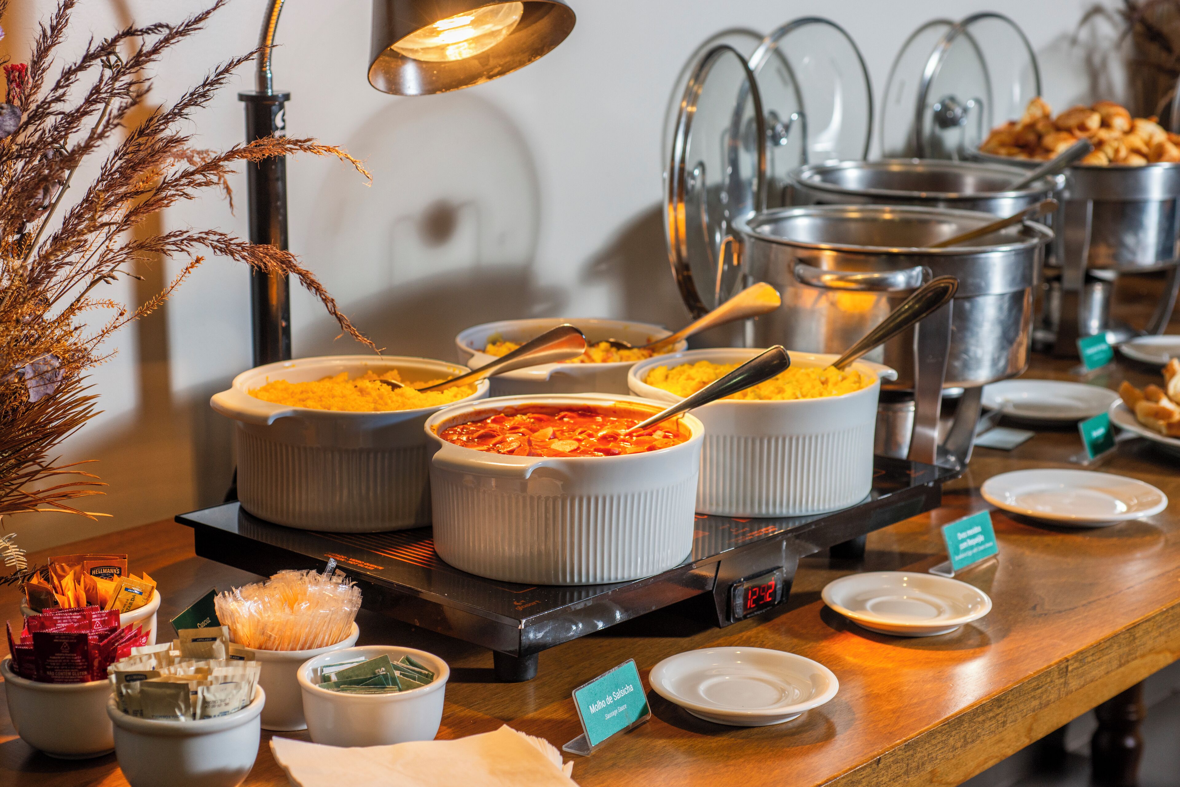 A buffet setup with multiple serving dishes and a clock displaying 12:20.