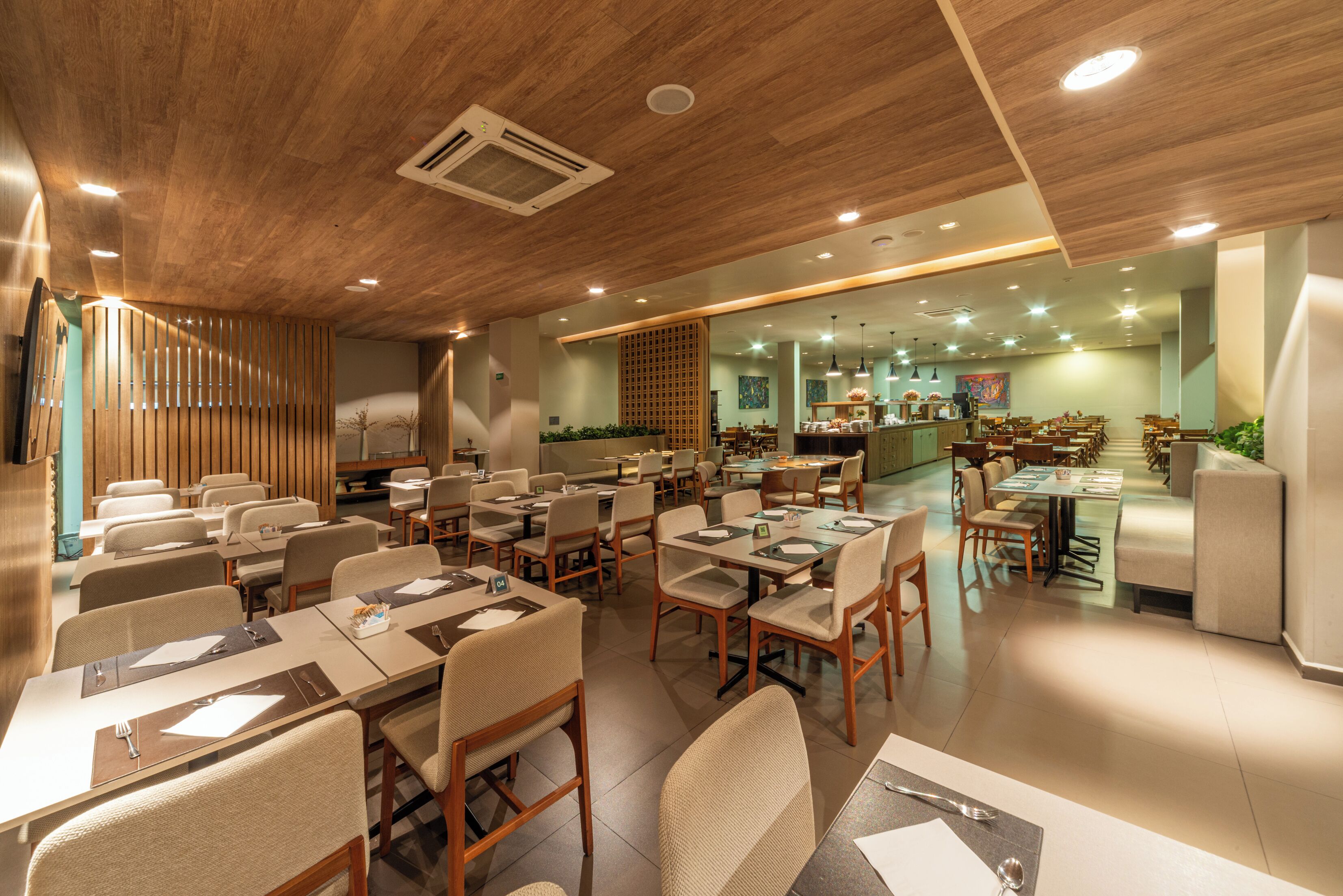 A spacious restaurant with multiple dining areas, wooden ceiling, and modern lighting.